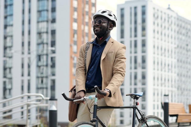 Feliz joven empleado afroamericano con casco de ciclismo