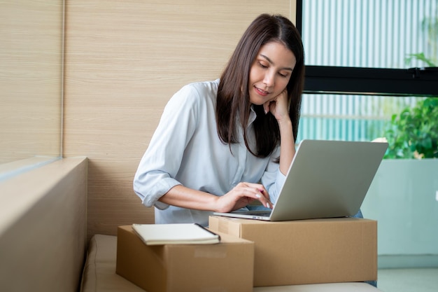 Foto feliz joven empresaria asiática sonríe por el éxito de ventas después de comprobar el pedido