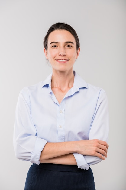 Feliz joven empresaria elegante en camisa blanca de pie delante de la cámara en aislamiento