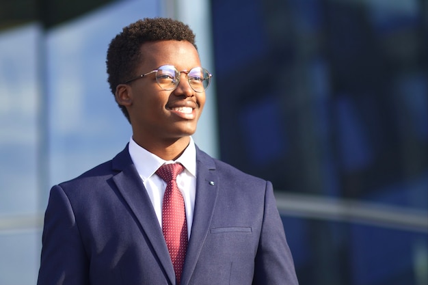 Feliz joven empresario africano afroamericano negro en traje y gafas sonriendo al aire libre