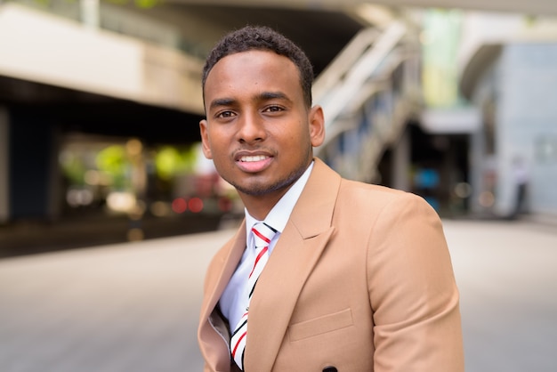 Feliz joven empresario africano guapo sonriendo en la ciudad al aire libre
