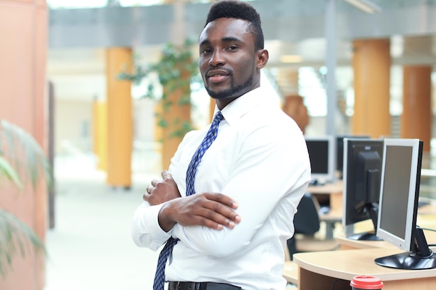 Feliz joven empresario afroamericano mirando la cámara en el lugar de trabajo en la oficina.