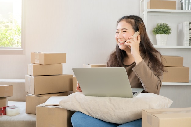 Feliz joven empresario asiático, hablando por teléfono inteligente con el cliente para el orden de tachuela