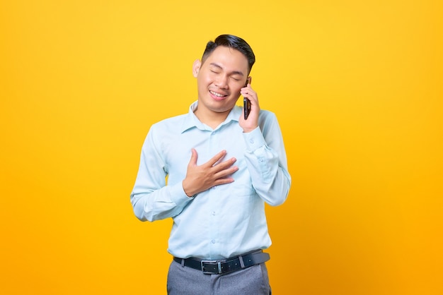 Feliz joven empresario guapo hablando por teléfono inteligente y manteniendo otras palmas en el pecho