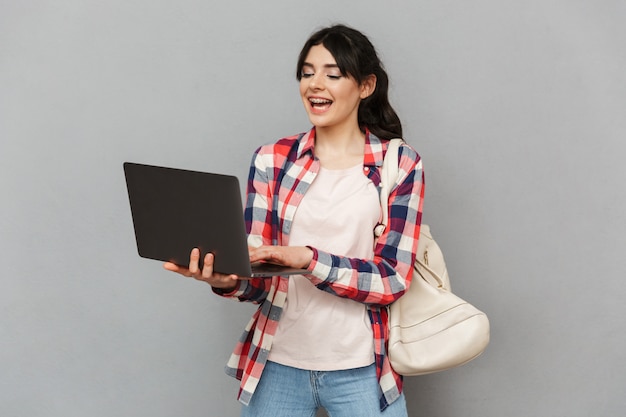 Feliz joven estudiante usando la computadora portátil.