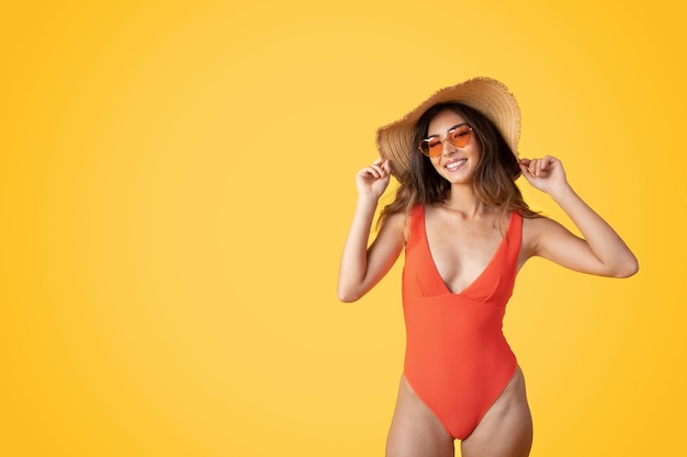 Foto feliz joven europea delgada con sombrero de traje de baño y gafas de sol disfruta de un viaje de descanso en el tiempo libre