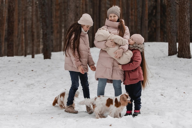 Feliz joven familia caucásica juega con un perro en invierno en un bosque de pinos