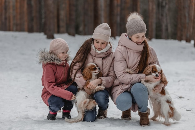 Feliz joven familia caucásica juega con perros en invierno en un bosque de pinos