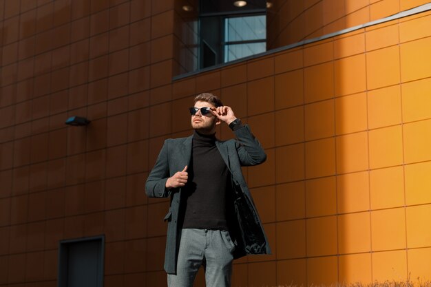 Feliz joven de gafas negras y un abrigo gris