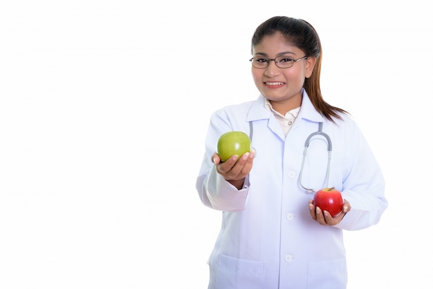 Feliz joven gorda médico persa sonriendo mientras da una manzana