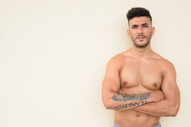 Feliz joven guapo musculoso persa sin camisa con los brazos cruzados