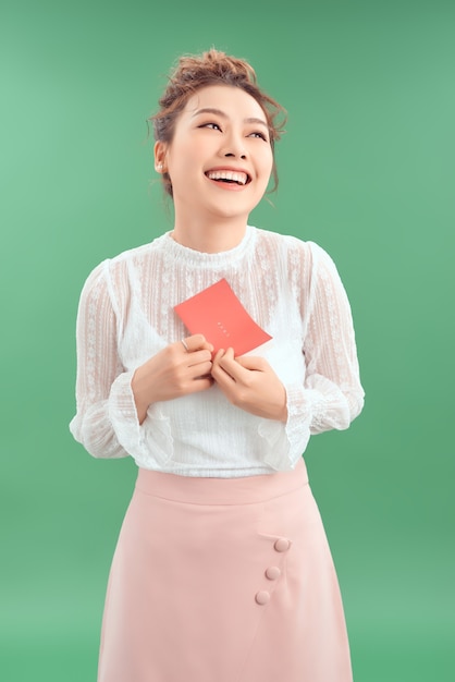 Feliz joven hermosa chica asiática con una postal de amor San Valentín sobre fondo verde