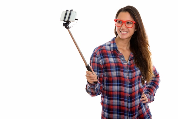 Foto feliz joven hermosa mujer hipster tomando selfie con teléfono en selfie stick