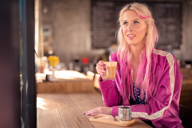 Feliz joven hermosa mujer rubia pensando y relajándose en la cafetería.