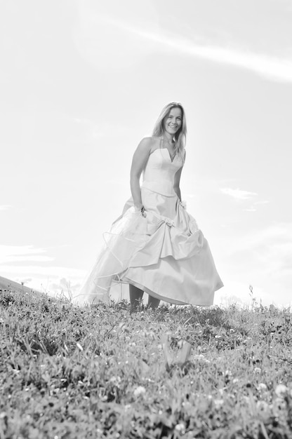 feliz joven hermosa novia después de la ceremonia de la boda diviértete al aire libre en la pradera al atardecer