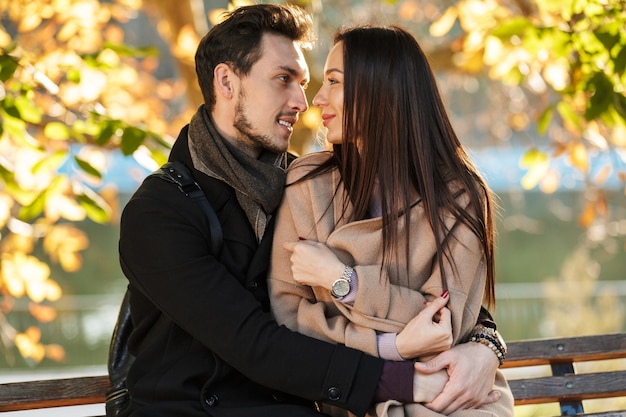 feliz joven hermosa pareja amorosa posando caminando al aire libre en la naturaleza del parque sentado en un banco.