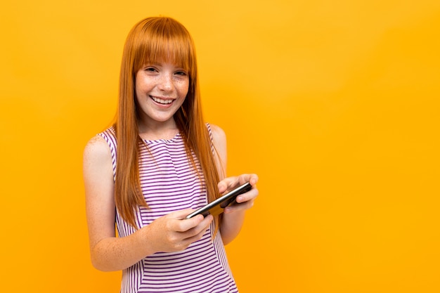 Feliz joven con hir rojo y gran sombrero rojo disfrutar de su vida y jugar juegos telefónicos aislados en blanco