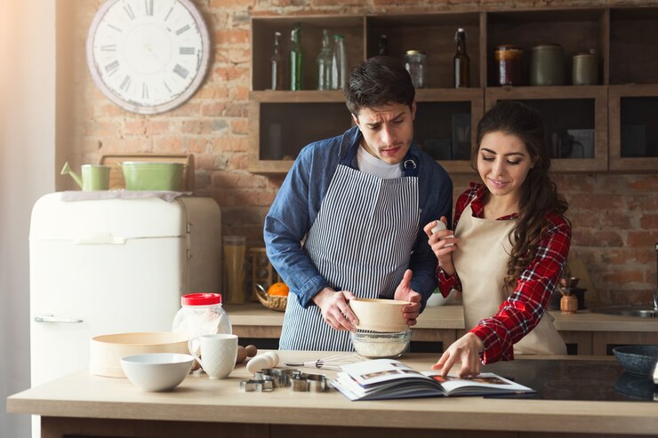 Foto feliz joven y hombre horneando pastel y buscando receta en cocina tipo loft. familia joven cocinando en casa.