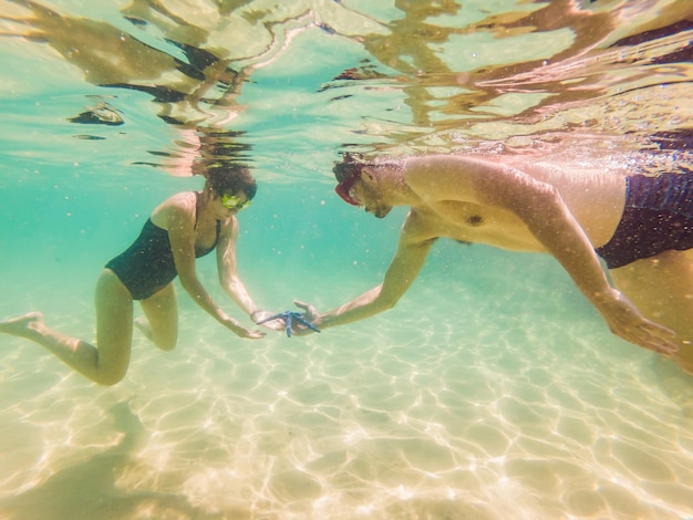 Feliz joven hombre y mujer nadando bajo el agua en el océano tropical