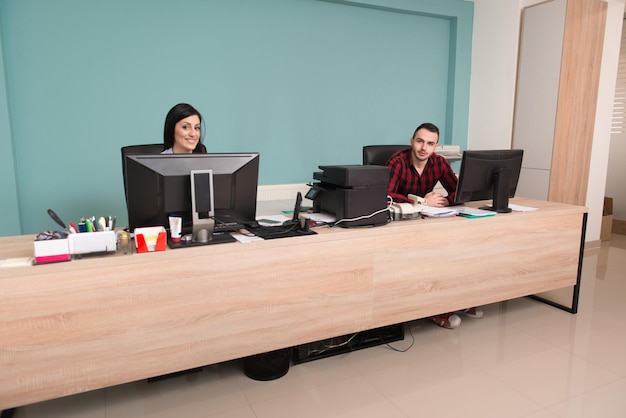 Feliz joven hombre y mujer de negocios trabajan en la oficina moderna en la computadora