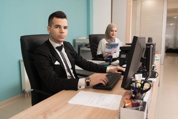 Feliz joven hombre de negocios y mujer musulmana trabajan en la oficina moderna en la computadora