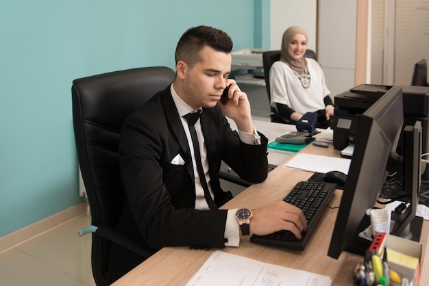 Feliz joven hombre de negocios y mujer musulmana trabajan en la oficina moderna en la computadora