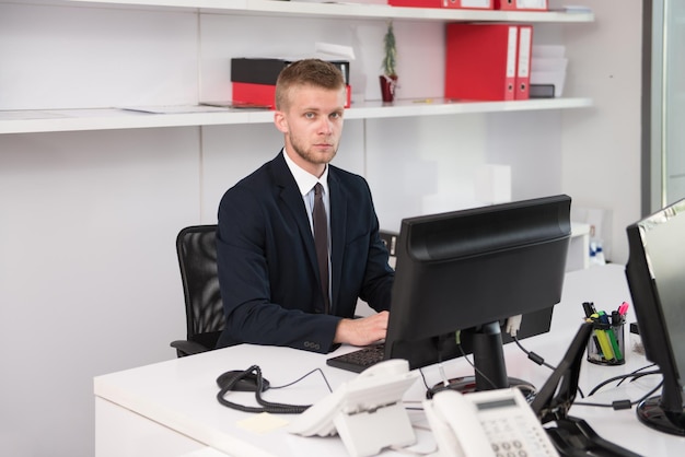 Feliz joven hombre de negocios trabaja en la oficina moderna en la computadora