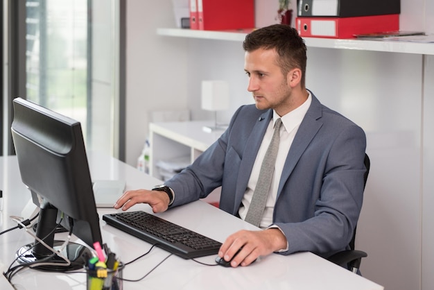 Feliz joven hombre de negocios trabaja en la oficina moderna en la computadora