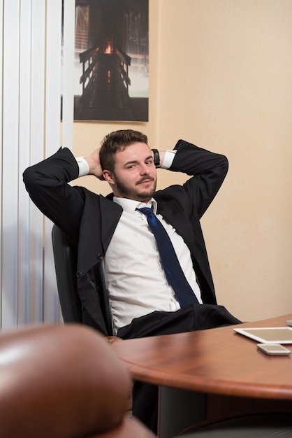 Feliz joven hombre de negocios trabaja en la oficina moderna en la computadora