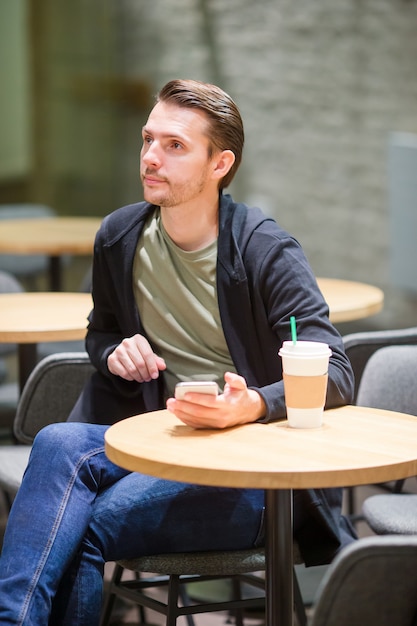 Feliz joven hombre urbano tomando café en la ciudad europea al aire libre