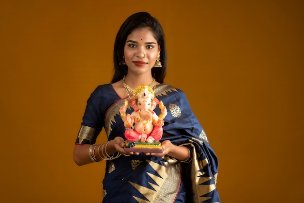 Feliz joven india posando con la estatua de Ganesha con motivo del Festival de Ganesh