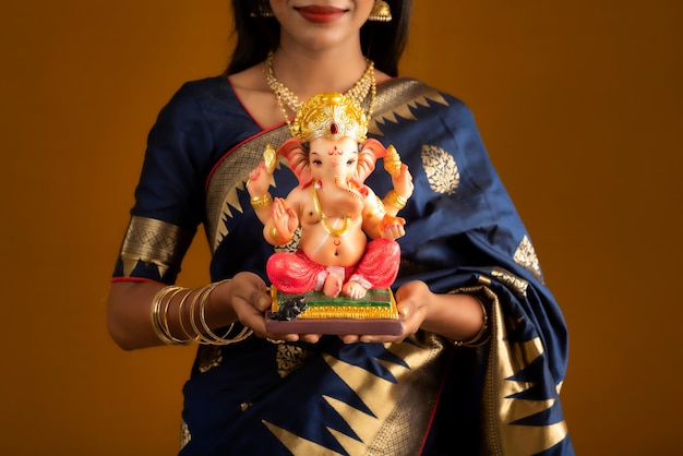 Feliz joven india posando con la estatua de Ganesha con motivo del Festival de Ganesh