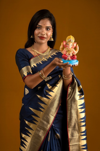 Feliz joven india posando con la estatua de Ganesha con motivo del Festival de Ganesh