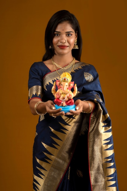 Feliz joven india posando con la estatua de Ganesha con motivo del Festival de Ganesh