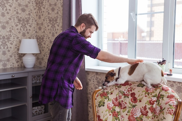 Feliz joven jugando con su perro en casa