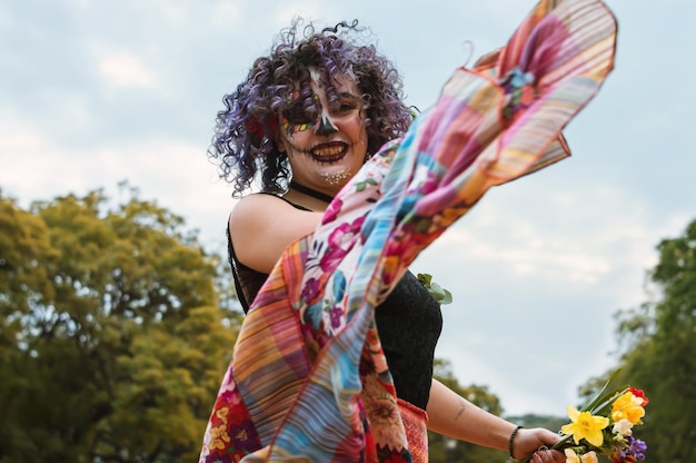 Feliz joven latina con maquillaje de catrina practicando danza folclórica en el parque