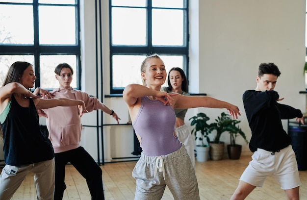 Feliz joven líder femenina del grupo de danza de moda que muestra un nuevo movimiento