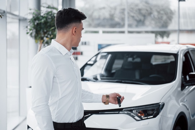 Feliz joven con llaves en las manos, suerte comprar un coche.