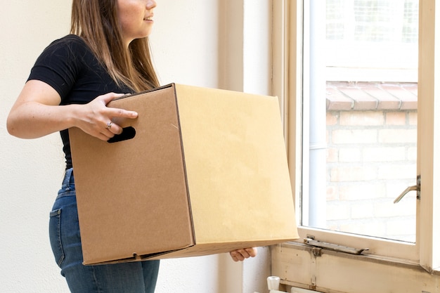 Feliz joven llevando una caja de cartón en movimiento