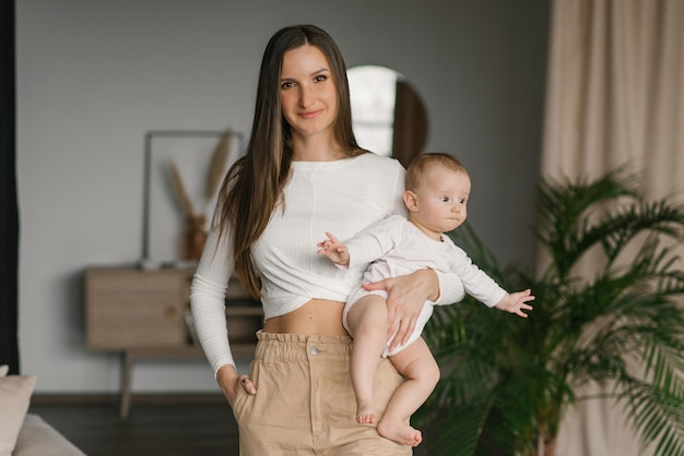 Feliz joven madre amorosa sostiene a un niño pequeño un hijo un bebé en casa en sus brazos