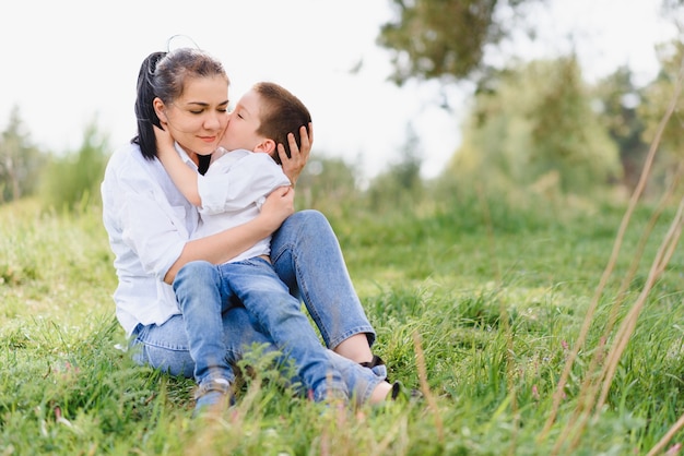 Feliz joven madre está jugando con su bebé en un parque en un césped verde