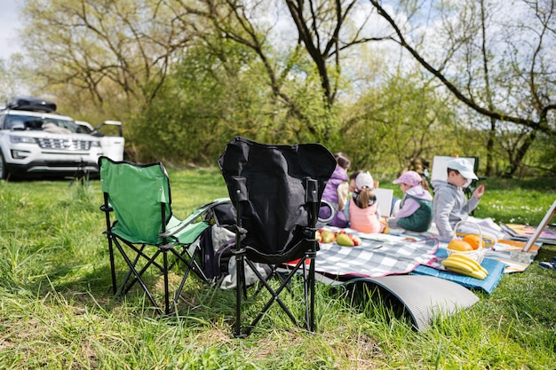 Feliz joven madre de familia y niños divirtiéndose y disfrutando al aire libre en una manta de picnic pintando en el jardín de relajación del parque de primavera