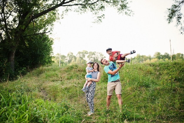 Feliz joven madre de familia padre dos hijos hijo en la naturaleza divirtiéndose