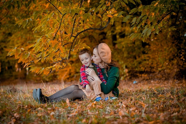 Feliz joven madre jugando y divirtiéndose con su pequeño hijo en el cálido día de otoño en el parque Feliz concepto familiar Día de la Madre