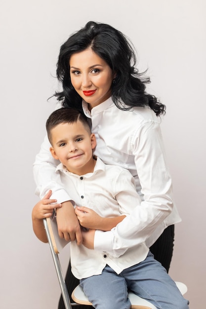 Feliz joven madre con un niño sobre fondo gris claro