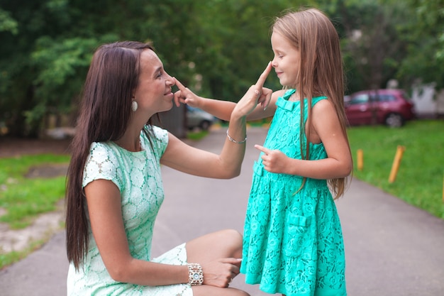 Feliz joven madre y su hija divirtiéndose al aire libre