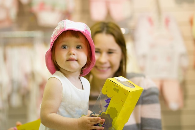 Feliz joven madre y su hija en el sombrero divirtiéndose en la tienda