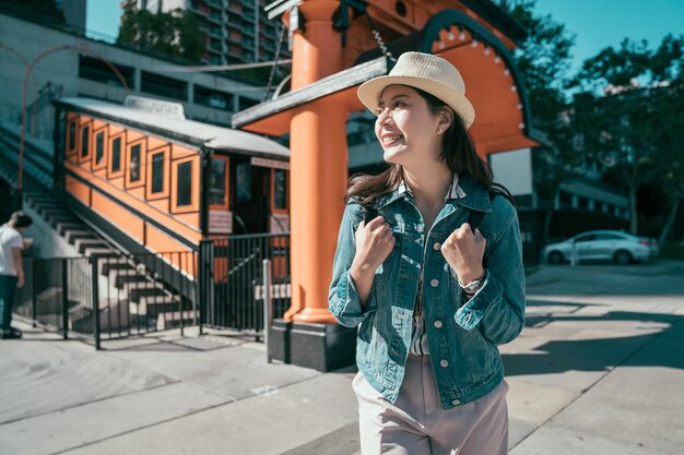 feliz joven mochilero con sombrero de paja sonriendo saliendo del tren de vuelo de los ángeles en los ángeles. viajero femenino viaje en funicular. hermosa mujer disfruta del sol al aire libre en la cara alegre.