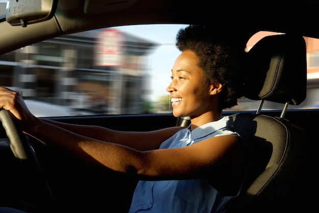 Feliz joven mujer africana conduciendo un coche