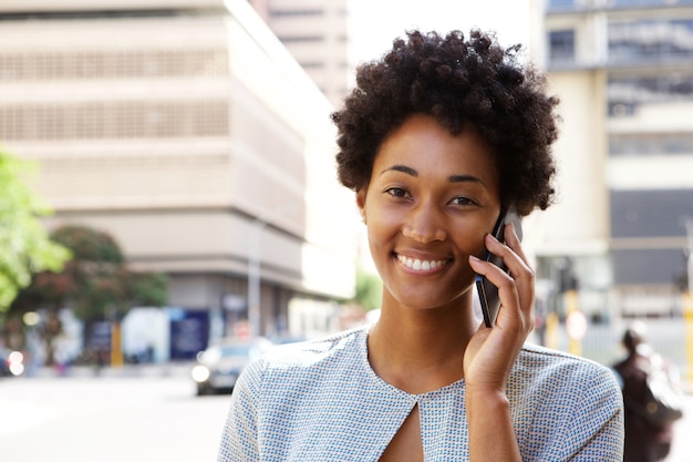 Feliz joven mujer africana hablando por teléfono móvil